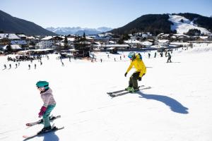 dos personas están esquiando por una pista cubierta de nieve en Appartements Landhaus Waidmannsheil, en Seefeld in Tirol