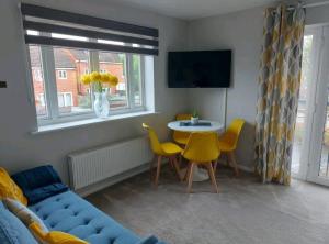 a living room with a couch and a table and yellow chairs at 2 Bedroom Apartment in Exhall