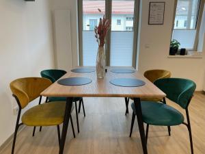 une table en bois avec des chaises vertes et un vase de fleurs dans l'établissement LIGHTPLACE • Design • Boxspring • Balkon • 2 Smart TV •Innenstadt, à Brunswick