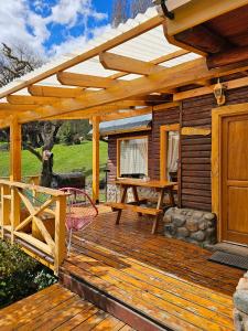 a wooden deck with a pergola and a picnic table at La Yaya - Villa Turismo in El Bolsón