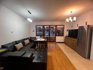 a living room with a black leather couch and a refrigerator at Lion King Bjelasnica in Bjelašnica