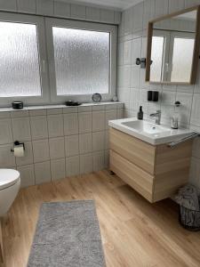a bathroom with a sink and a toilet and a mirror at Ferienwohnung Fehn in Rhauderfehn