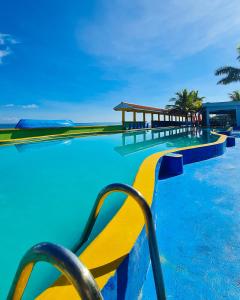 a swimming pool with blue water and yellow benches at Hotel Partenon Beach in La Ceiba