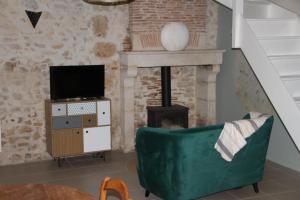 sala de estar con sofá verde y chimenea en La p'tite maison en Lussas-et-Nontronneau