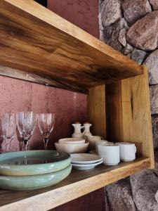a wooden shelf with plates and wine glasses on it at Bendita Piedra Suites, Las Compuertas Lujan de Cuyo in Ciudad Lujan de Cuyo