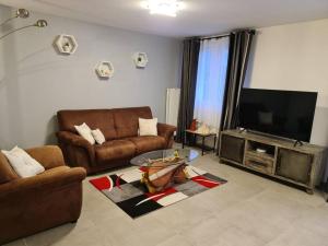 a living room with two couches and a flat screen tv at Charmante maison Les Cèdres Bleus in Loon-Plage