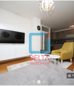 salon z telewizorem i żółtym krzesłem w obiekcie Grand centar apartman w Sarajewie