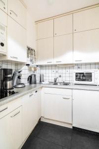 uma cozinha branca com armários brancos e um micro-ondas em Haus Iderhoff Appartment 28 em Norderney