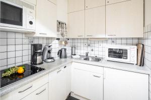 uma cozinha branca com um lavatório e um micro-ondas em Haus Iderhoff Appartment 28 em Norderney