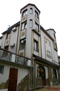 a tall white building with a clock tower at Family hotel The Castle in Shumen