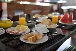 a table with plates of food and cups of orange juice at Pousada Recanto Oriental in Palmas