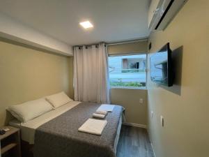 um pequeno quarto com uma cama e uma janela em Pousada Tissiano em Florianópolis