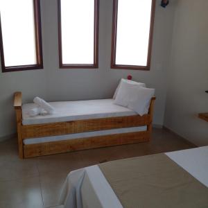 Bett in einem Zimmer mit 2 Fenstern in der Unterkunft Chalé Vale Sereno Classic in Camanducaia