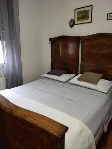 ヴェローナにあるB&B Maddalena Di San Zenoのベッドルーム1室(大型ベッド1台、木製ヘッドボード付)