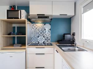 a kitchen with white cabinets and a sink at Compact 4 person chalet in Friesland in De Veenhoop