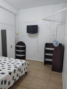 a bedroom with a bed and a flat screen tv at Kitnet Avenida in Imbituba