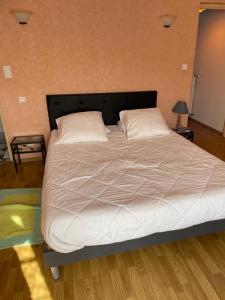 Una cama con sábanas blancas y almohadas en un dormitorio en Aux 3 Loups, en Châtenois