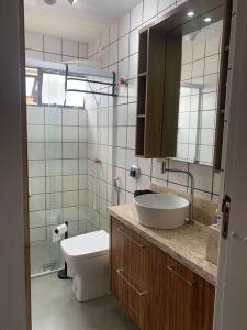 a bathroom with a sink and a toilet and a mirror at Jurerê - Direto na Praia in Florianópolis