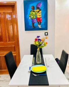 a dining room table with a vase of flowers on it at Appartement meublé avec Spa jacuzzi privatif in Mbour +8 photos