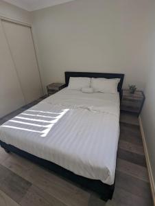 a bedroom with a large bed with white sheets and pillows at Huge Holiday Home 4Beds 2Baths in Gladstone near Shopping Center in Gladstone