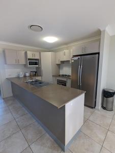 a kitchen with a stainless steel refrigerator and cabinets at Huge Holiday Home 4Beds 2Baths in Gladstone near Shopping Center in Gladstone