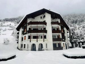un gran edificio de apartamentos con nieve en el suelo en Cadras, en Tinzen