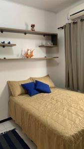 Un dormitorio con una cama con almohadas azules. en Lar aconchego, lot. Búzios do francês, en Marechal Deodoro