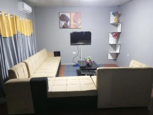 a living room with two white couches and a tv at Ramachi apartments in Livingstone