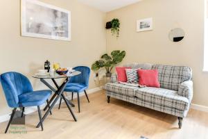 a living room with a couch and a table and chairs at 1 bed flat for two close to train station with private parking by Eagle Owl Property in Worthing
