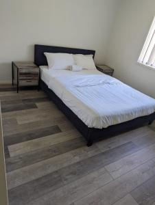 Bett in einem Schlafzimmer mit Holzboden in der Unterkunft Christa's 4Bedroom Entire Private House Gladstone City in Gladstone