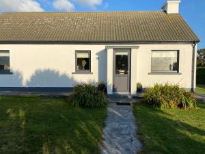 Biały dom z drzwiami i trawą w obiekcie Joe and Mary's Cottage w mieście Doolin