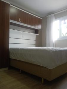 ein Schlafzimmer mit einem Bett und einem Fenster in der Unterkunft Aconchego Apartamentos da Serra in Canela