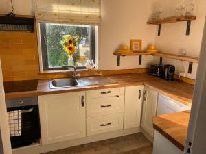 eine Küche mit weißen Schränken, einem Waschbecken und einem Fenster in der Unterkunft Joe and Mary's Cottage in Doolin