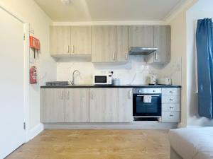 una cucina con armadi in legno e forno a microonde di Large Cosy Property 15min from Central London a Londra