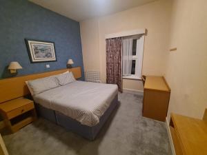 a small bedroom with a bed and a window at Devon Towers Hotel in Bournemouth