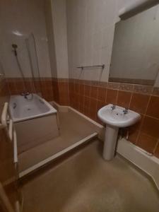 ein Badezimmer mit einem Waschbecken und einer Badewanne in der Unterkunft Devon Towers Hotel in Bournemouth