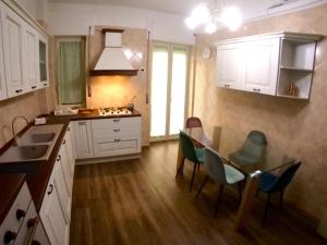 una cocina con mesa y sillas y una cocina con armarios blancos. en The House of Grandma en Nápoles