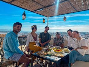 eine Gruppe von Menschen, die an einem Tisch mit Essen sitzen in der Unterkunft Tangier Kasbah Hostel in Tangier