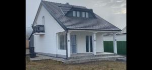 a small white house with a black roof at Vila Tom & Jerry in Raška