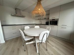 Lakeside Cottage De Rijd في Nieuwe-Niedorp: مطبخ أبيض مع طاولة بيضاء وكراسي