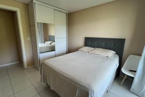 um pequeno quarto com uma cama e um espelho em Apto no terraço da rainha com vista para roda gigante e mar em Balneário Camboriú