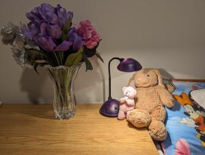 una mesa con un jarrón de flores púrpuras y dos animales de peluche en Bright Room full of love and warmth en Bowmanville