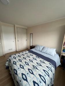 a bedroom with a bed with a blue and white blanket at Departamento céntrico in Valdivia