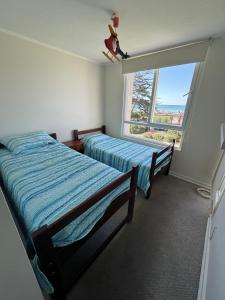2 Betten in einem Zimmer mit Fenster in der Unterkunft Departamento en playa herradura in Coquimbo