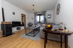 een woonkamer met een bank en een tafel bij Apartmani Rumora Gorski kotar in Tuk Vojni