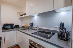 a kitchen with white cabinets and a black counter top at Metropolitan House, 1 Hagley Road in Birmingham