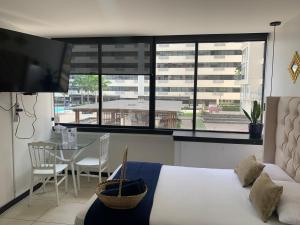 1 dormitorio con cama, mesa y vistas a un edificio en Ecusuites Jacuzzi Bellini Hidromasaje Privado, en Guayaquil