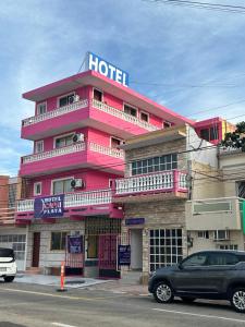 un hôtel rose avec une voiture garée devant lui dans l'établissement Hotel Capri Playa a una calle de la Playa Regatas, à Veracruz