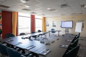 uma sala de conferências com mesas e cadeiras e um ecrã em Kyriad Chartres em Chartres