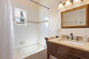 a bathroom with a tub and a sink and a mirror at Beautiful Home Steps from the beach + Side Porch in Daytona Beach +14 photos